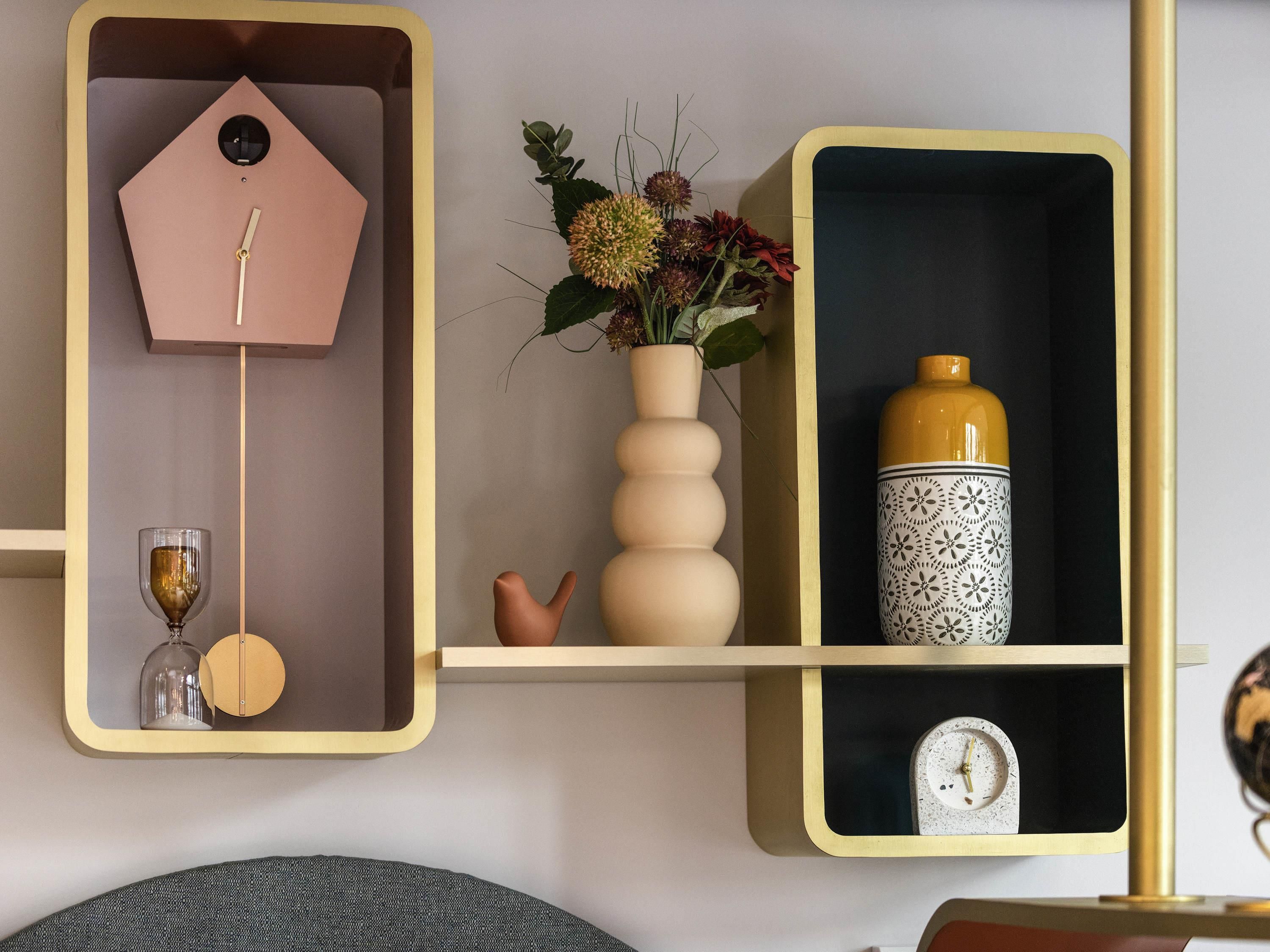 Ein Regal mit einer Uhr, einer Vase mit Blumen und einem Dekorationsgegenstand.