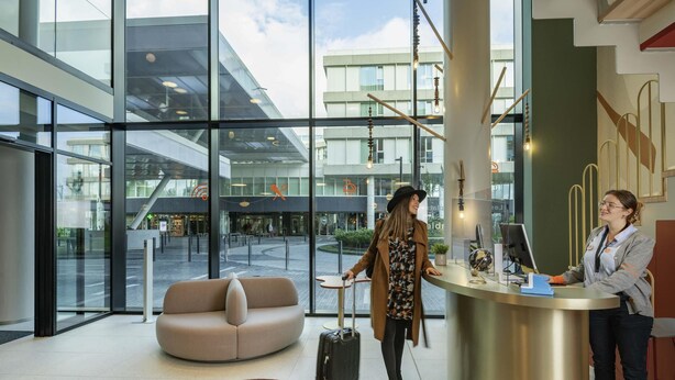 A modern lobby with a reception desk, a seating area, and large windows offering views of the outside. - Aparthotel Adagio Access Brussels Delta (Brussels)