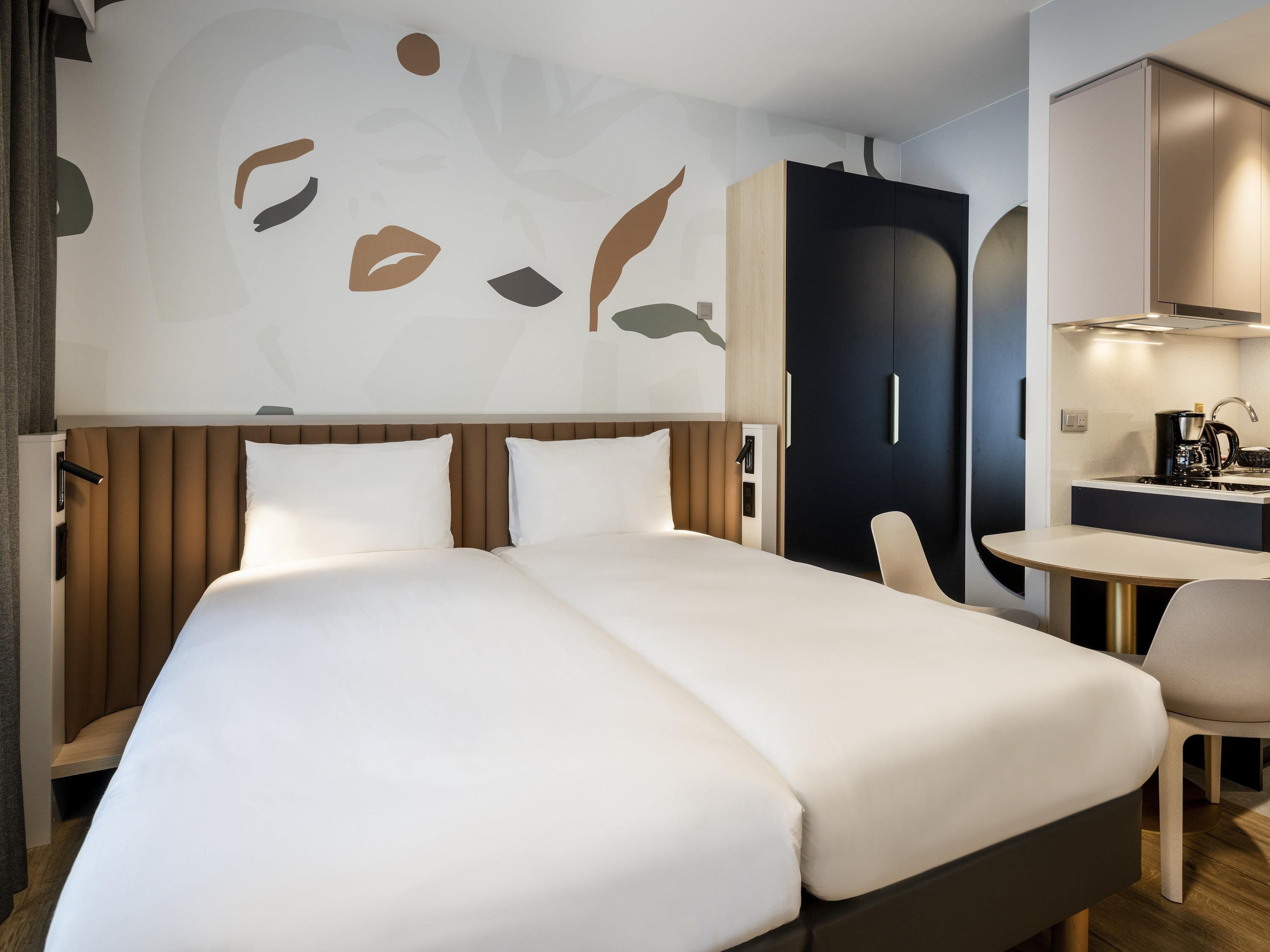 Et hotelværelse med en stor seng, et skrivebord og et tekøkken.