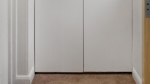 Valkoinen vaatekaappi, jossa on kaksi ovea ja kummassakin ovessa oma kahva.