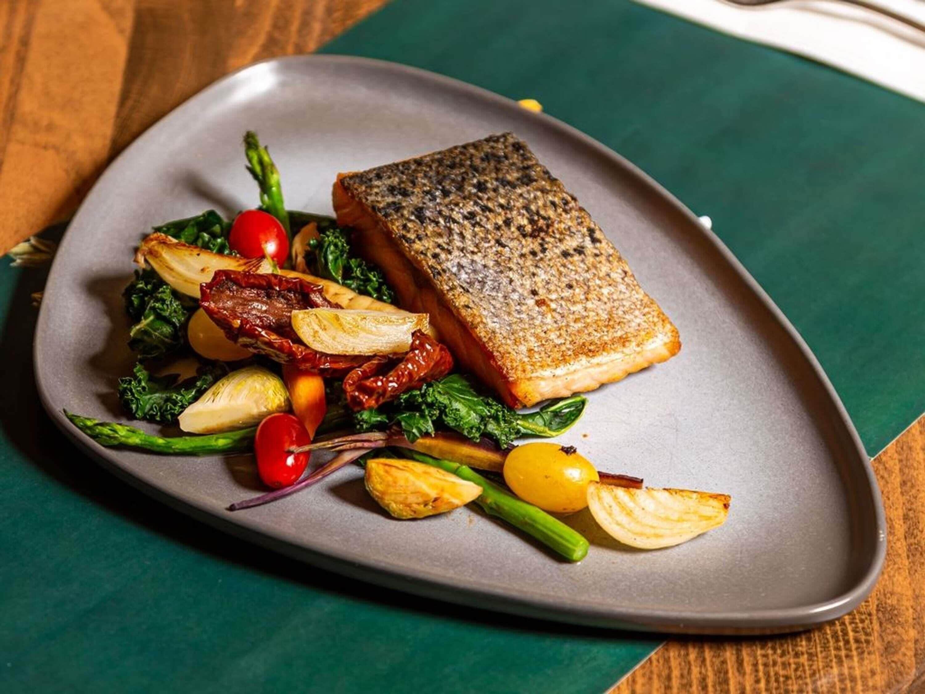 A plate of food with salmon, asparagus, cherry tomatoes, and roasted potatoes.
