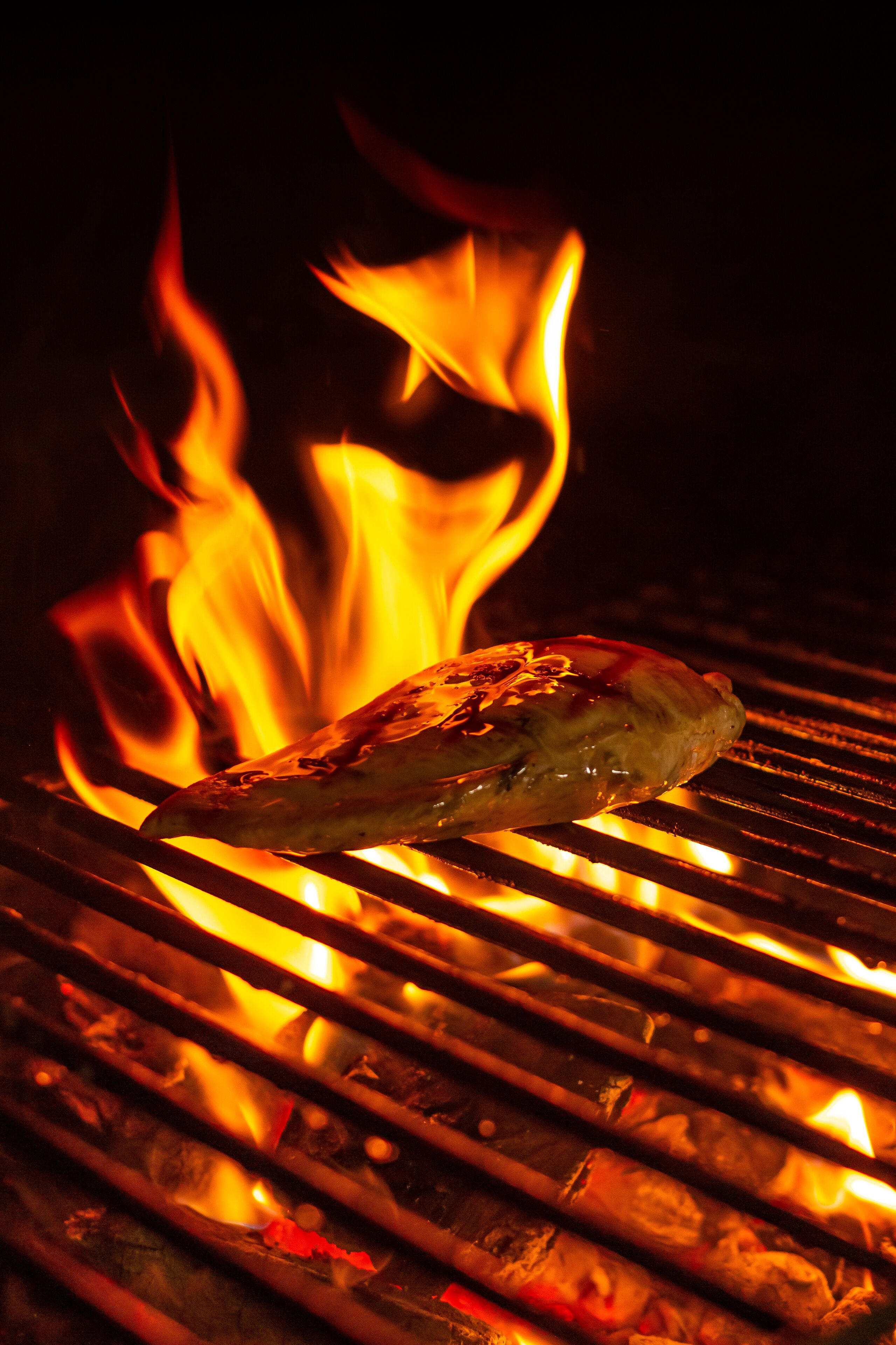 Une viande grillée sur un barbecue, avec des flammes apparentes.