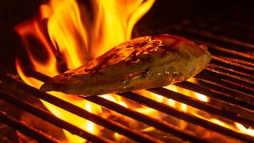 Une viande grillée sur un barbecue, avec des flammes apparentes.