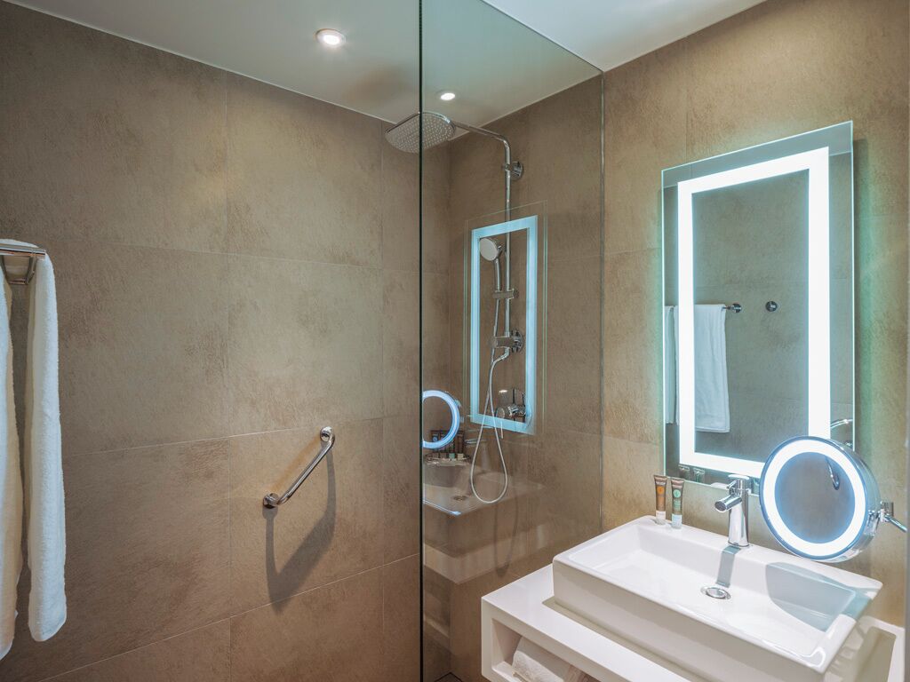 A modern bathroom with a glass shower enclosure, a vanity with a mirror, and a towel rack.