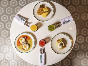 A round dining table with four plates of food, a glass of juice, and a glass of iced tea. - Novotel Mexico City Toreo  (Naucalpan)