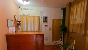 Un mostrador de recepción con un cartel que dice "BIENVENIDOS RECEPTION" y una planta a su lado.