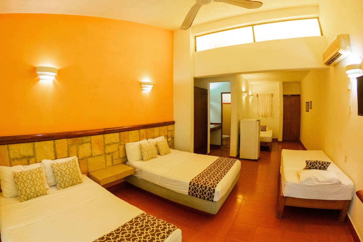 A hotel room with two beds, a ceiling fan, and a bathroom visible through an open door.