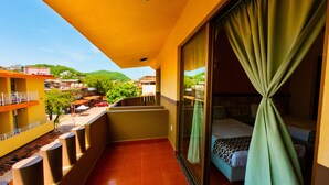 Un balcón con una cama, vistas de la ciudad y una cortina verde.
