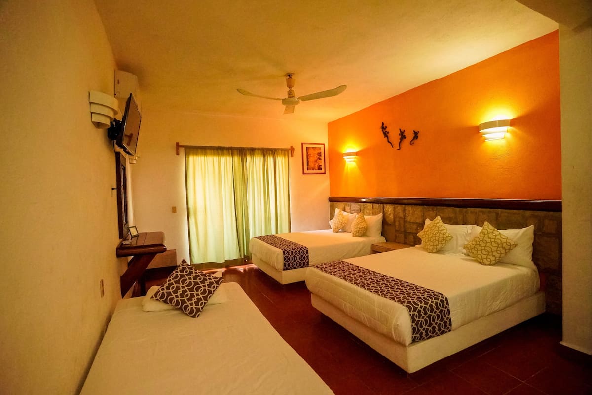 A hotel room with two beds, a ceiling fan, a nightstand, a lamp, and a window with curtains.