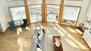 A spacious room with large windows offering a view of the water and greenery.