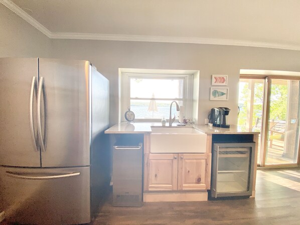A kitchen with a refrigerator, sink, and cabinets.