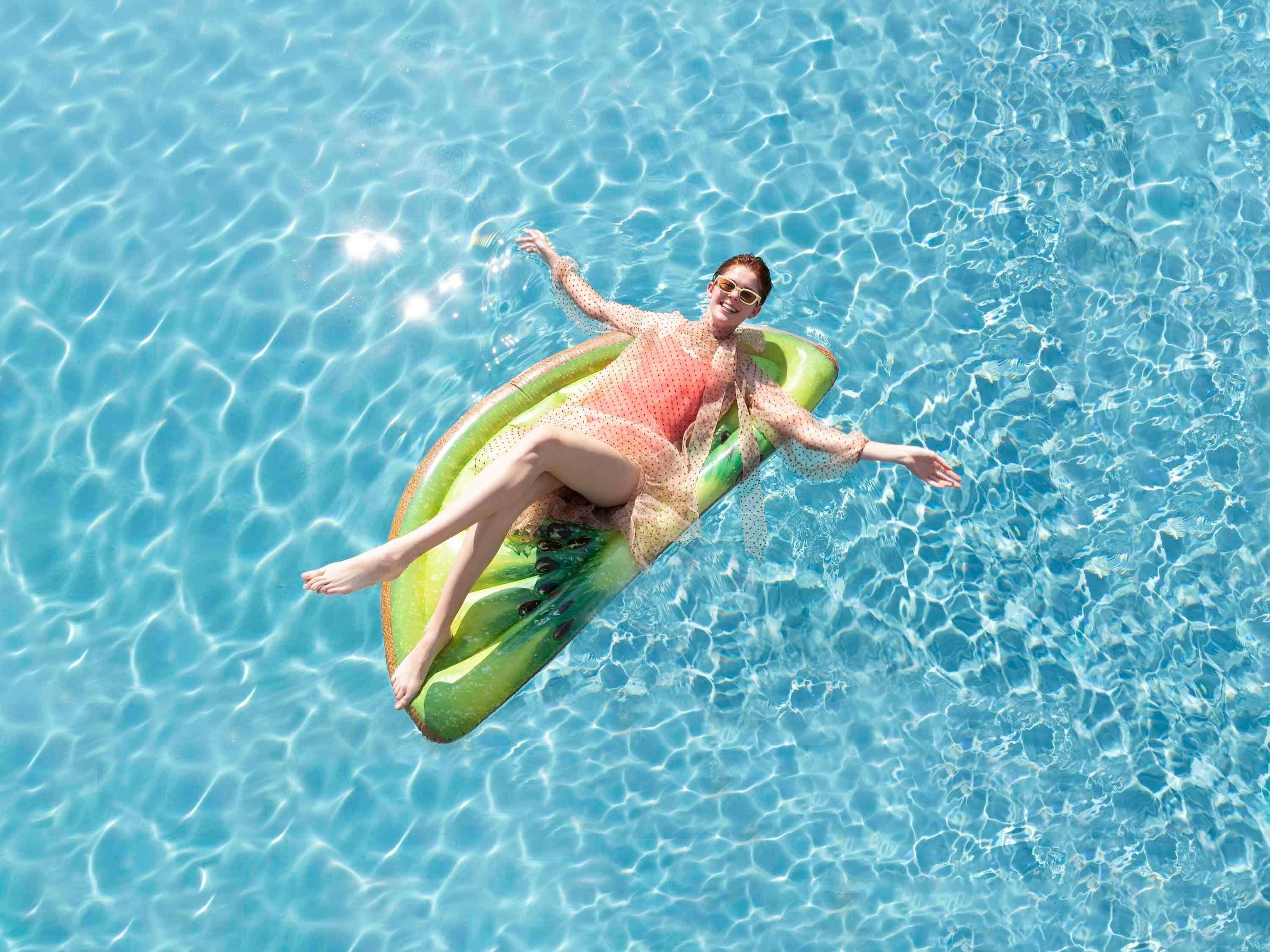 A person floating on a water-filled inflatable raft in a pool.