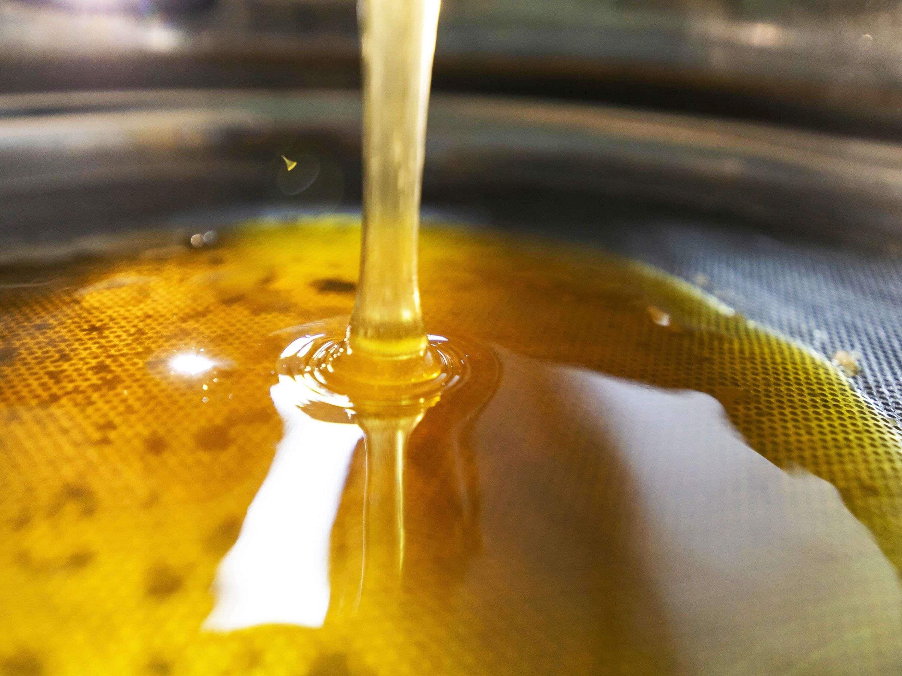 A close-up of a liquid with a reflective surface, possibly honey or syrup, with a clear drop in the center.
