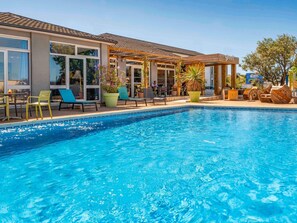 A swimming pool with lounge chairs and potted plants.