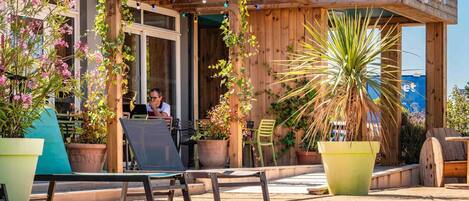 A poolside area with a wooden pergola, outdoor seating, and a sign that reads 'greet'.