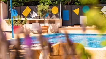 Una piscina al aire libre, sillones reclinables de piscina