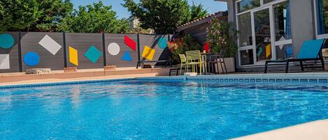 Una piscina con borde de azulejos, rodeada por una valla de diseños geométricos.