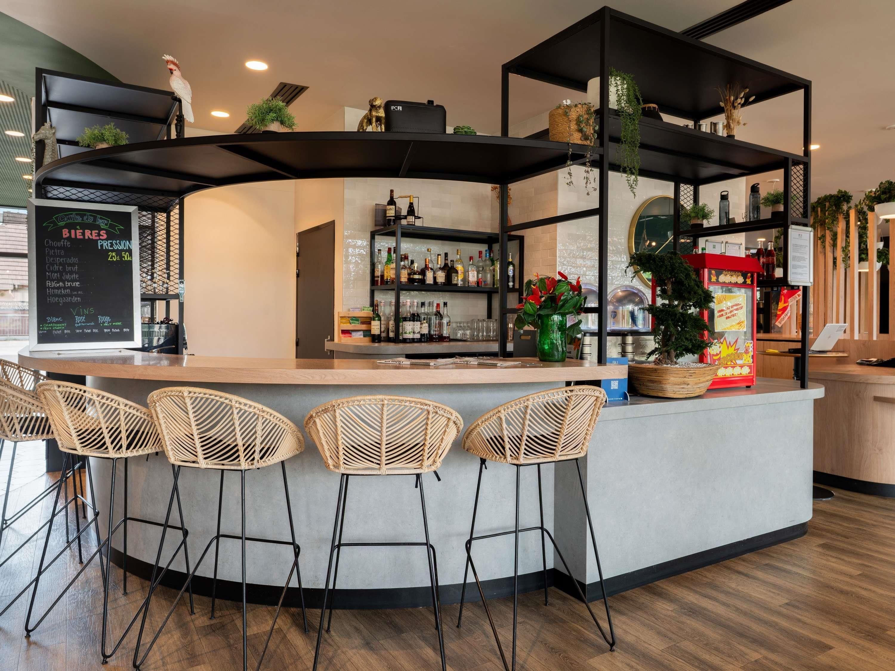 Zona de bar con mostrador, taburetes y estanterías llenas de botellas.