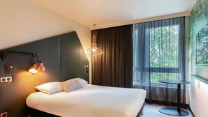 A hotel room with a bed, a desk, a lamp, and a window with curtains. - ibis Styles Rouen Centre Rive Gauche  (Rouen)