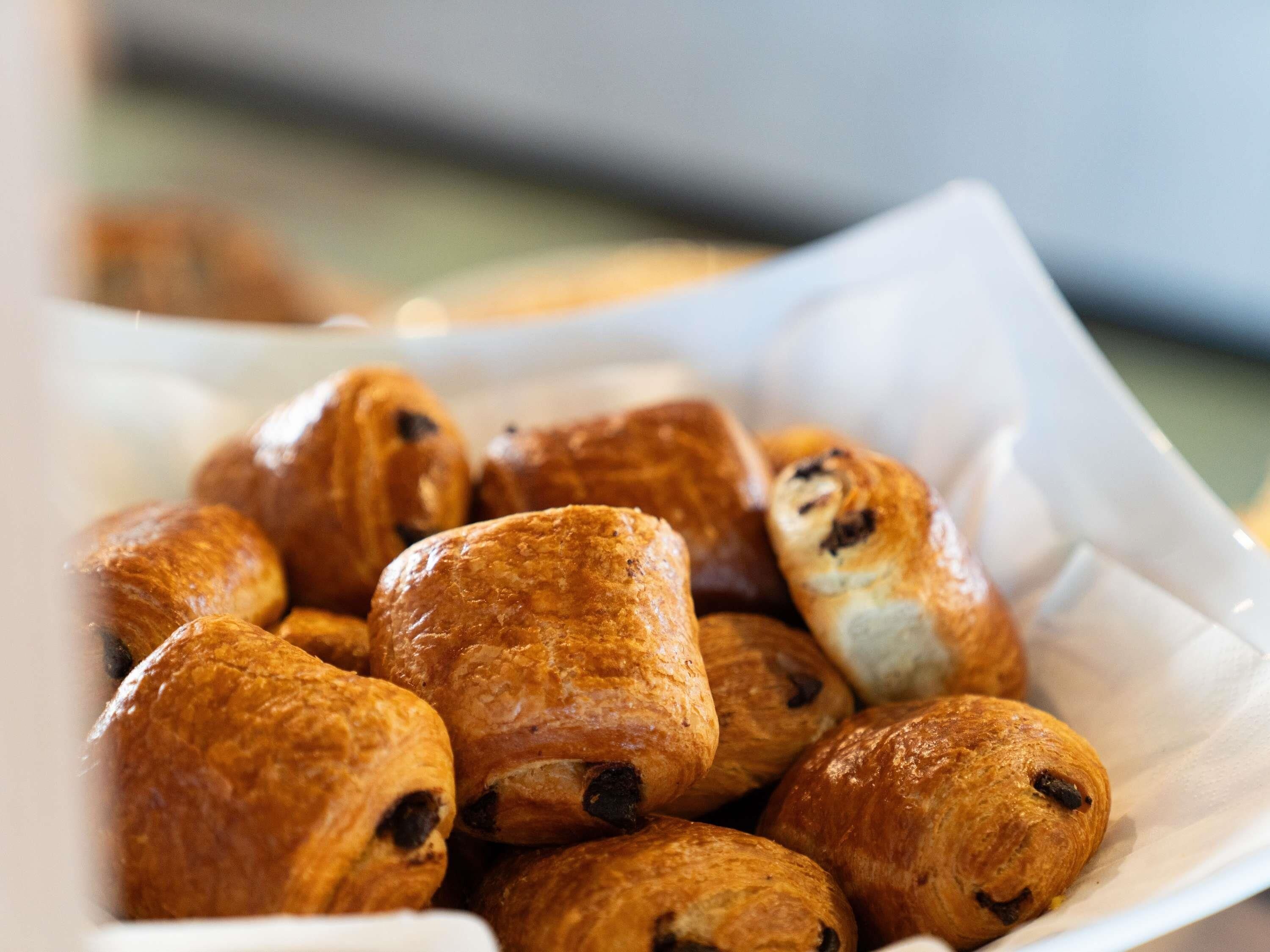 Een wit bord met verschillende ronde gebakjes, mogelijk croissants, met donkere vullingen.