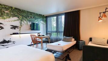 A hotel room with two beds, a desk with a chair, a television, and a window with curtains.