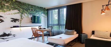 A hotel room with two beds, a desk with a chair, a television, and a window with curtains.