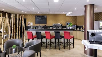 Zona de bar con mostrador, asientos y una máquina de café.