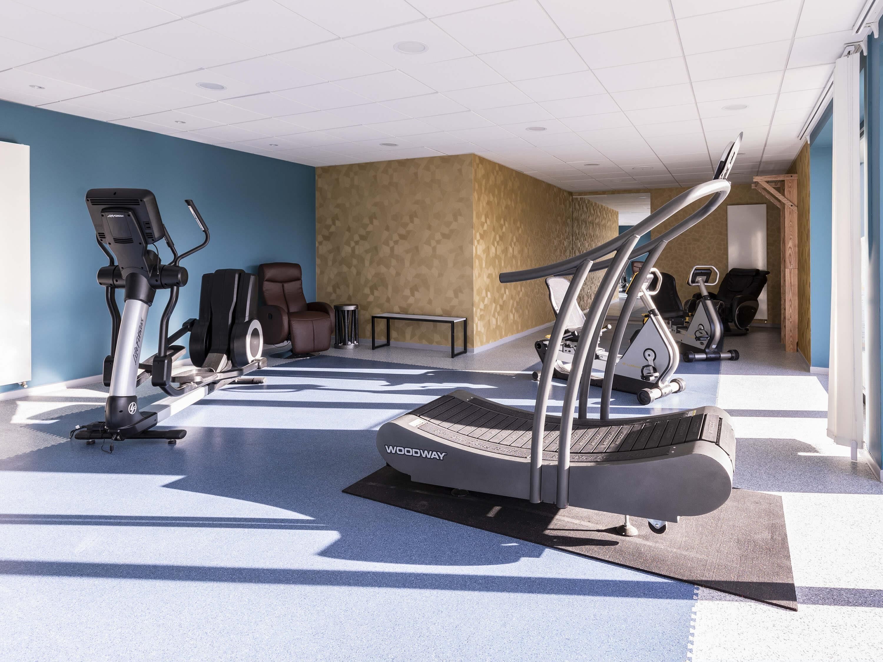 A fitness center with treadmills, stationary bikes, and exercise chairs.