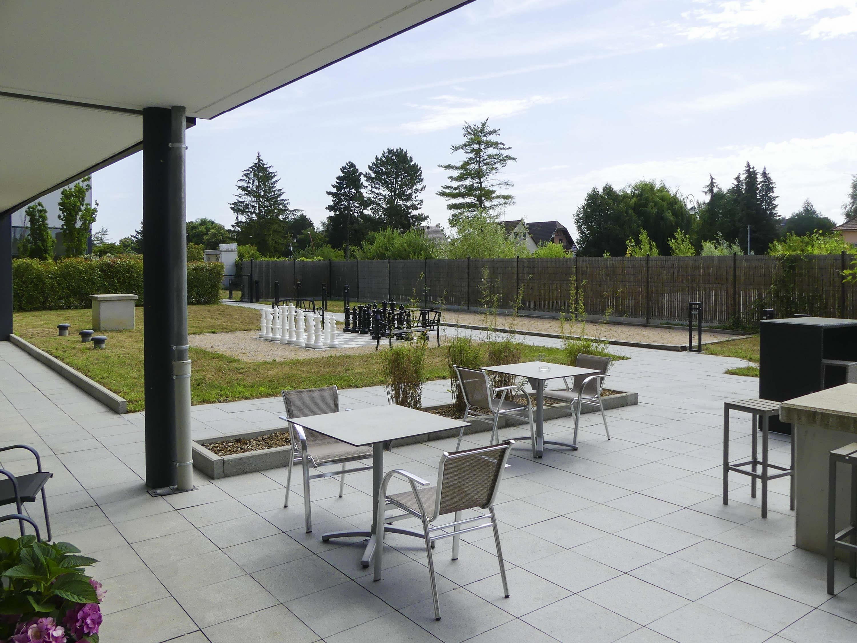 Une terrasse extérieure avec un jeu d’échecs, des tables et des chaises.
