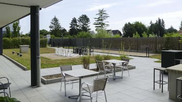 Une terrasse extérieure avec un jeu d’échecs, des tables et des chaises.