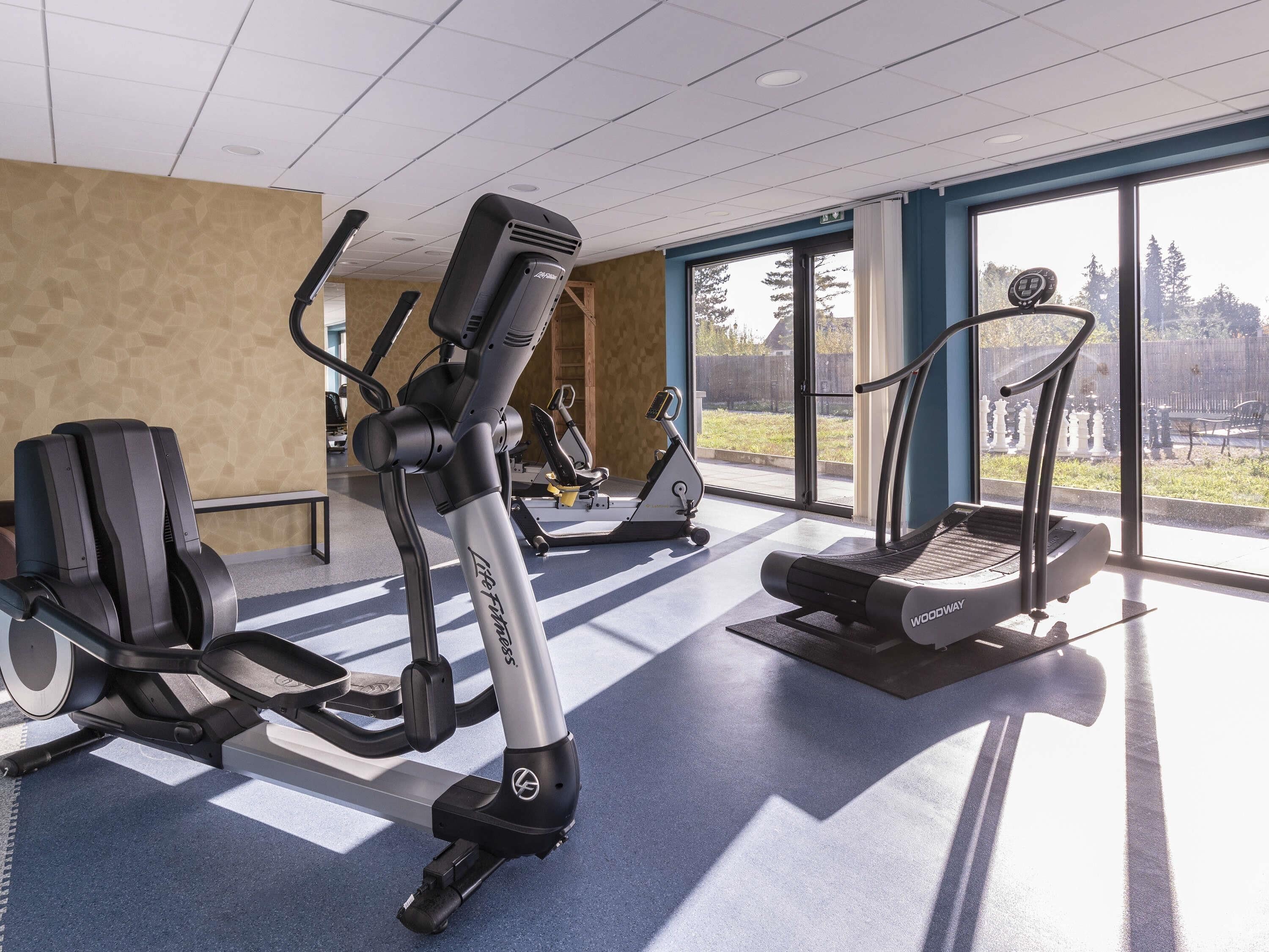 A gym with cardio machines, a treadmill, and a stationary bike.
