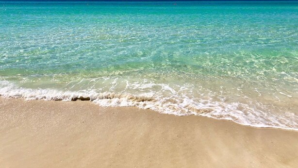 Una playa con agua turquesa cristalina y una orilla arenosa.