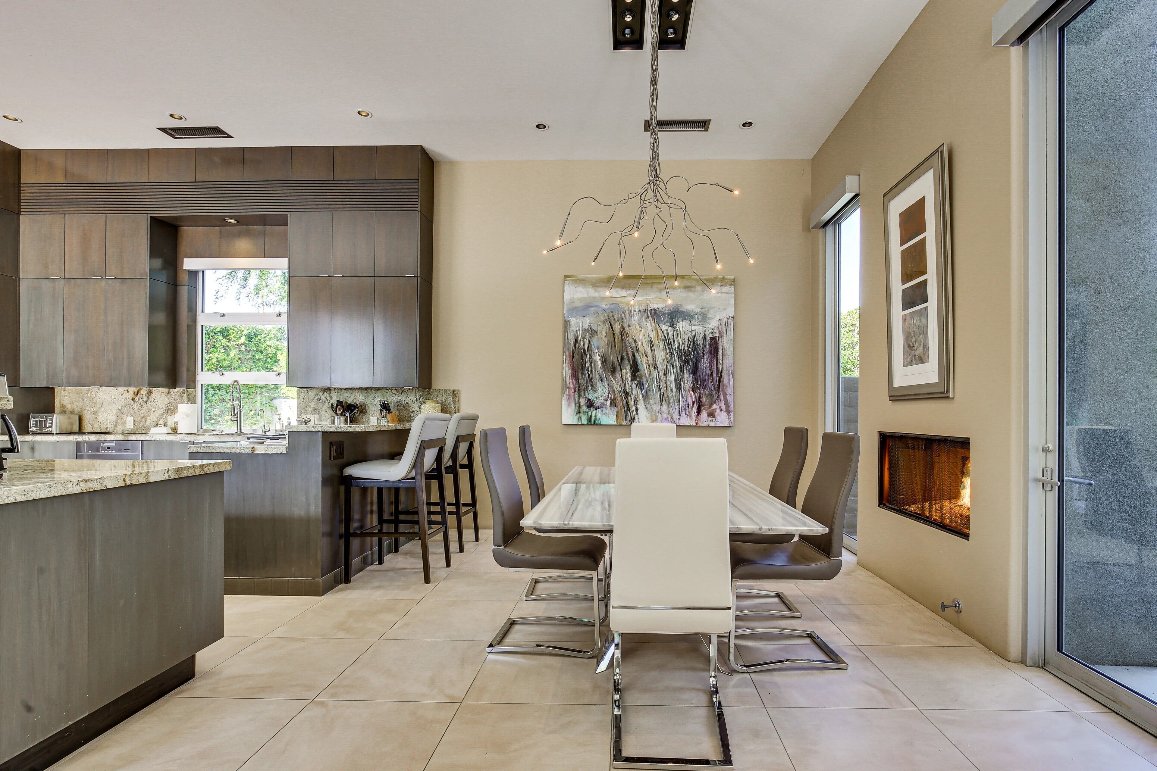 A modern kitchen with a large island, dining area with chairs, and a fireplace.