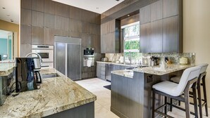 Una cucina moderna con isola centrale, elettrodomestici in acciaio inossidabile e un'ampia finestra che garantisce luce naturale.