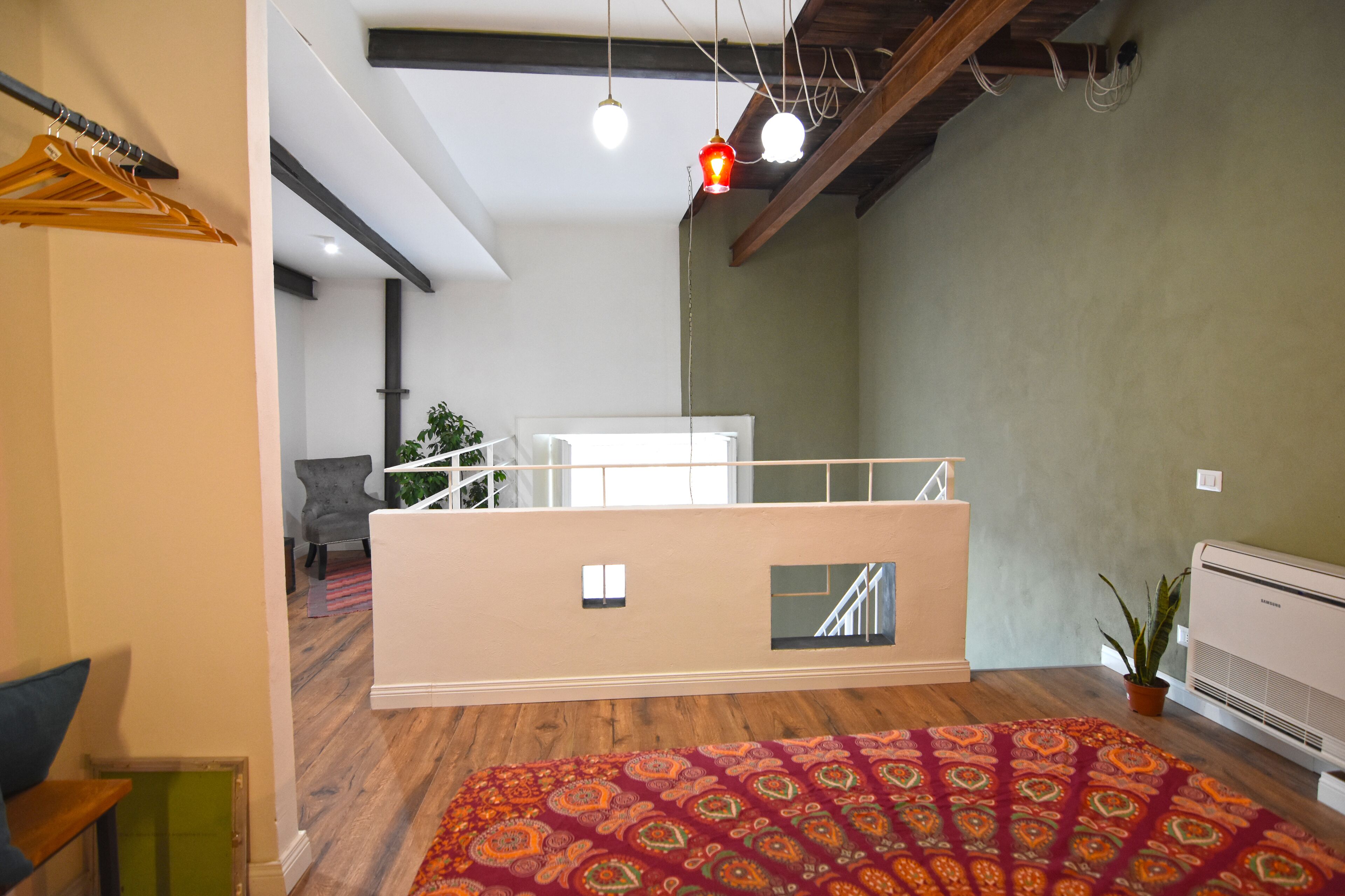 Une pièce spacieuse avec un grand lit, un petit balcon et une vue sur un escalier.