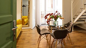 Uma sala de jantar com mesa e cadeiras, um sofá amarelo e um espelho.