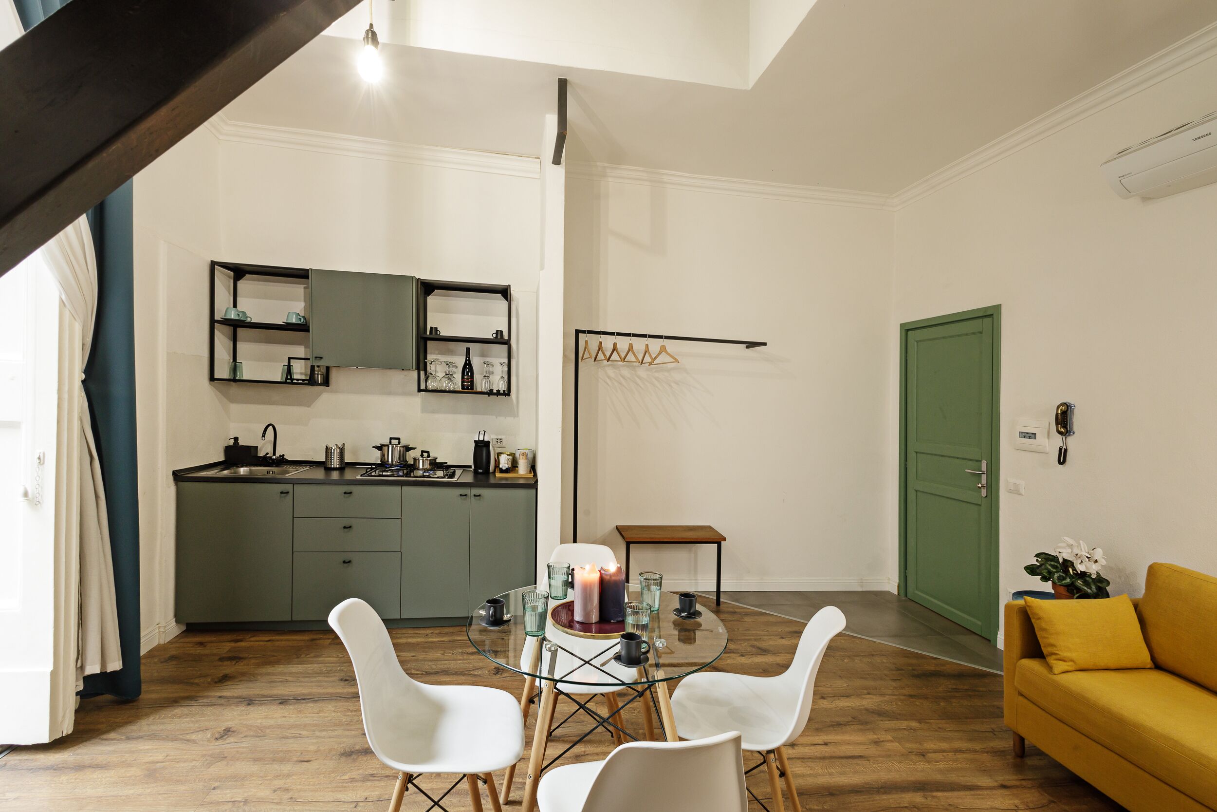 Una cocina moderna con comedor, una puerta verde y un sofá amarillo.
