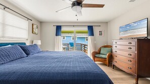 Een slaapkamer met een bed, een dressoir, een stoel, een plafondventilator en een televisie.