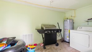 A laundry room with a washing machine, a dryer, a water heater, and a grill.