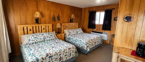 Quarto estilo cabana de madeira com duas camas, aquecedor, cafeteira e janela com cortinas.