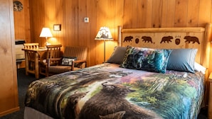A wooden-paneled room with a bed, a desk, a chair, and two lamps. - Sunshine Motel and Cabins (Ontonagon)