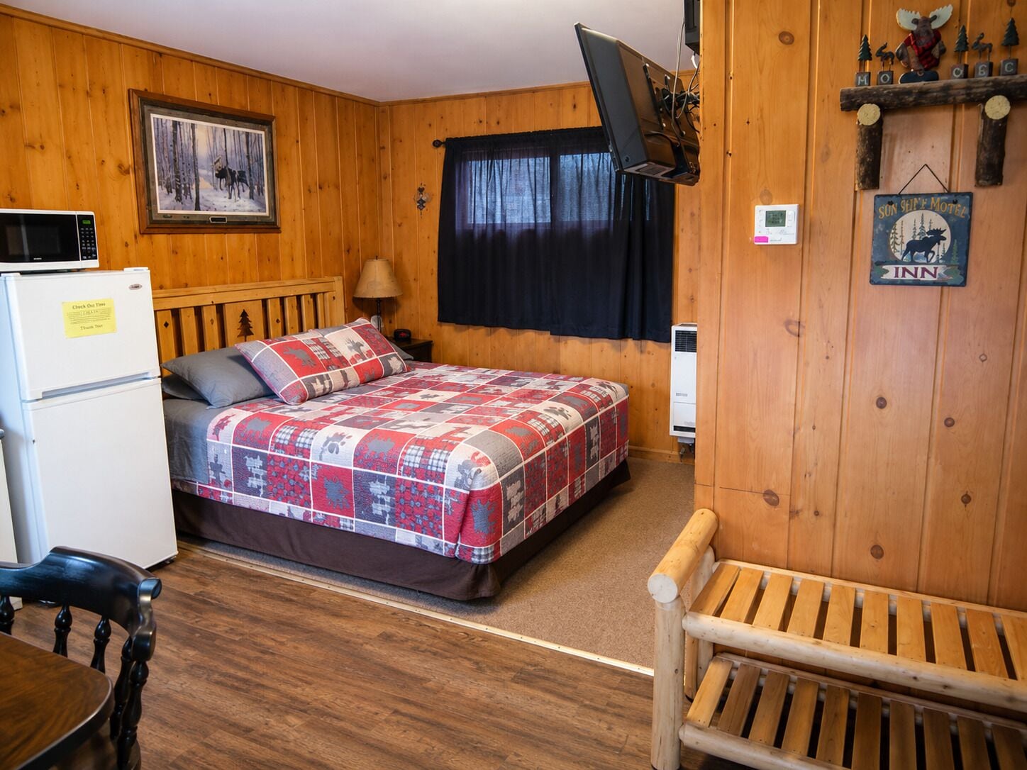 Une chambre confortable avec un lit, un bureau, une chaise, un téléviseur fixé au mur et un panneau indiquant qu’il s’agit d’un motel.