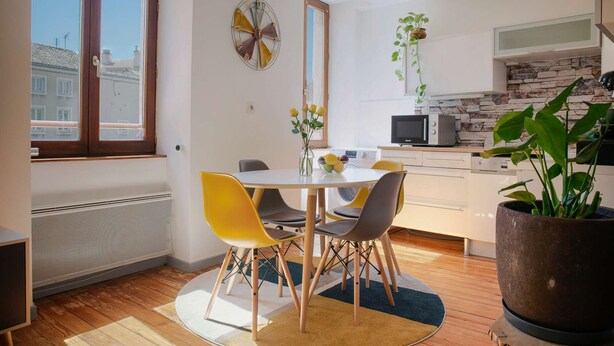 Een moderne keuken met een eethoek, met een ronde tafel, stoelen en een potplant.