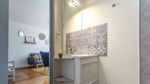 Een moderne badkamer met een wit wastafelmeubel, betegelde vloeren en een klein plankje.