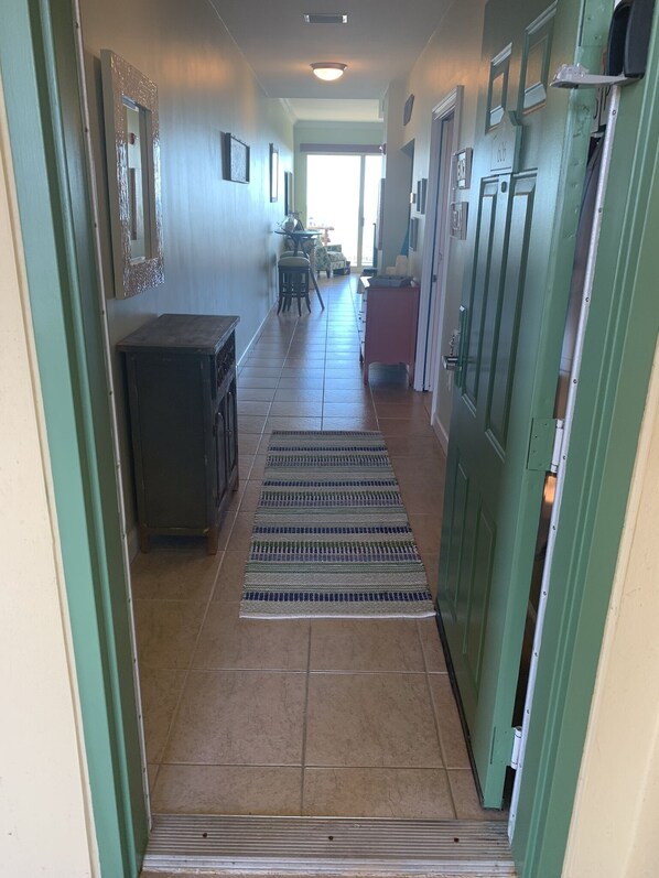Un corridoio con pavimento piastrellato, un tappeto a righe e una porta con un numero.