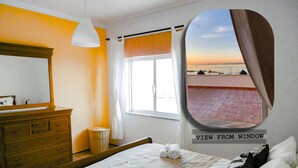 Een slaapkamer met een bed, een kaptafel, een spiegel, een raam met uitzicht op het strand, en een uitzicht vanuit het raam.
