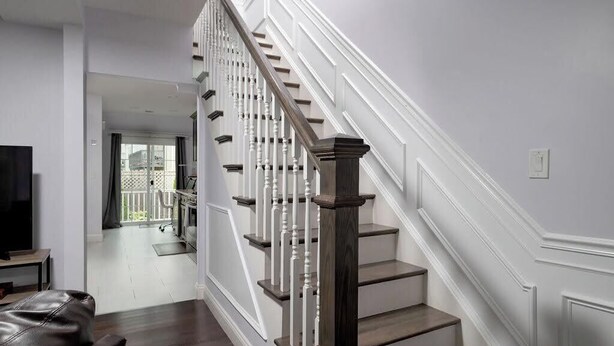 Eine Treppe mit weißen Geländern und dunklen Holzstufen, die zu einer zweiten Etage führt.