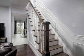Eine Treppe mit weißen Geländern und dunklen Holzstufen, die zu einer zweiten Etage führt.
