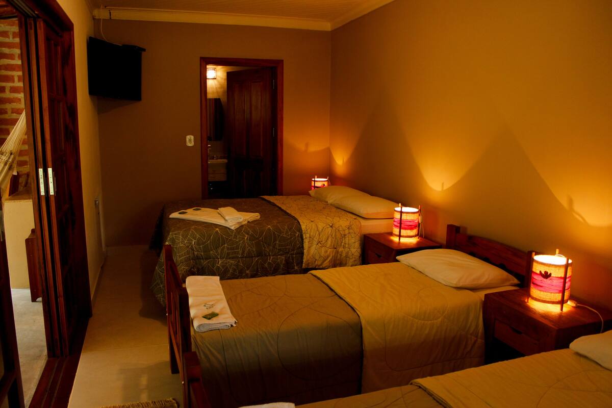 Habitación de hotel con dos camas, un televisor montado en la pared y una escalera que lleva a otra habitación.