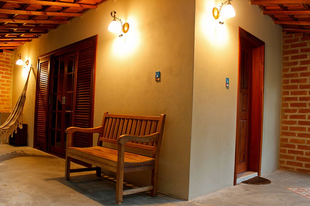A wooden bench in a hallway with a brick wall and wooden shutters.